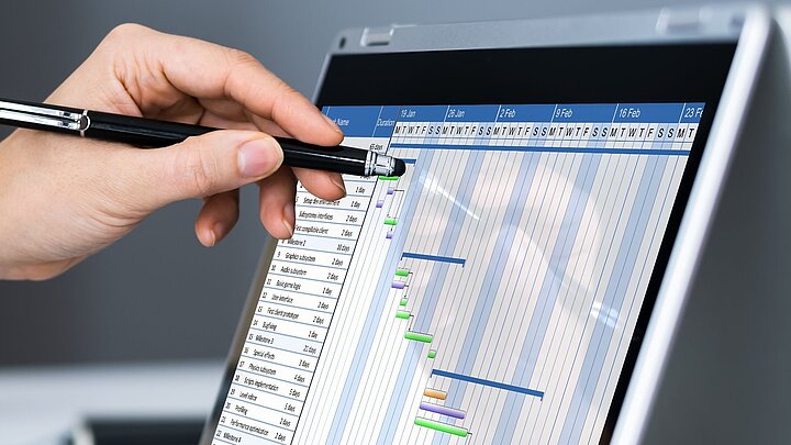 zdjęcie ilustracyjne. Dłoń zpiórem wskazuje na coś na tablecie