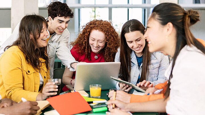 Grupa osób uśmiechniętych siedzących wokół laptopa